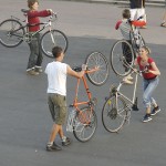 Participants mirroring each other's moves, bikes over shoulders and on back wheel