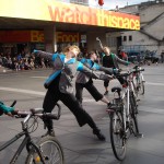 Diagonal line of costumed cyclists strike a pose