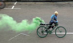 performer running with bike pouring green smoke from the back