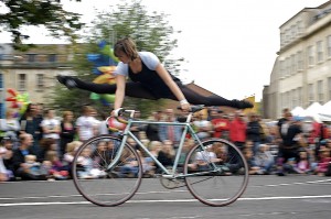 Performer does splits in the air balanced on moving bike