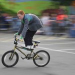 Young participant speeds past balancing on the cross bar of his bike
