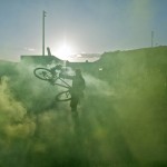 Performers spin their bikes around with green smoke pouring from the back