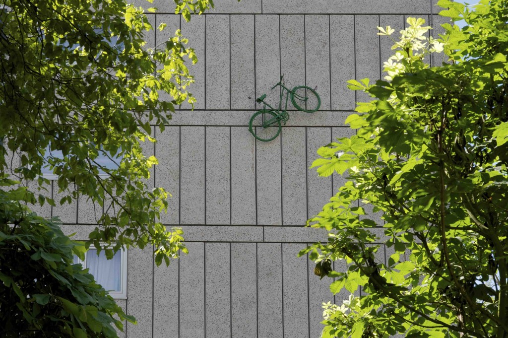 Green bicycle installed half way up the outside wall of a block of flats on the Alton Estate, Roehampton