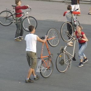 participants work in pairs with their bikes, one pair lifting bikes onto back wheels, another pair hold bikes over their shoulders through the frames