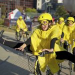 various images of Strictly Cycling performers with yellow helmets, yellow goggles, yellow rain macs cycling, walking with bikes, interacting with passers-by, street furniture & each other